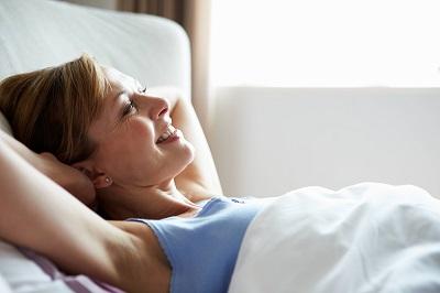 woman smiling in bed after TMJ treatment