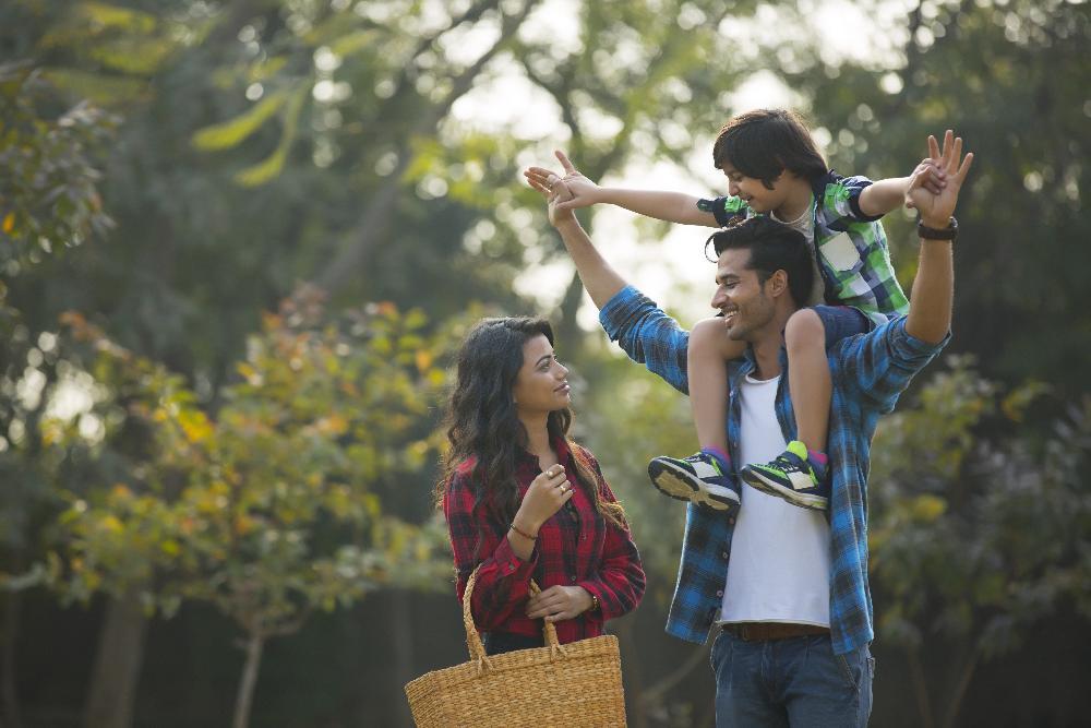 mother, father, and son smiling in park