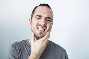 young man holding jaw from TMJ pain | clifton hill dentist