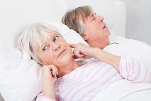 woman putting her fingers in her ears to not hear her husband snore