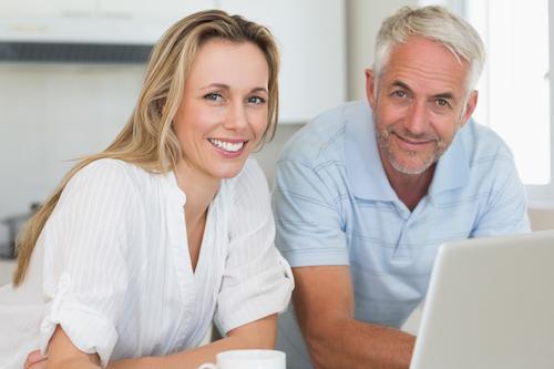 man and woman smiling while looking at computer