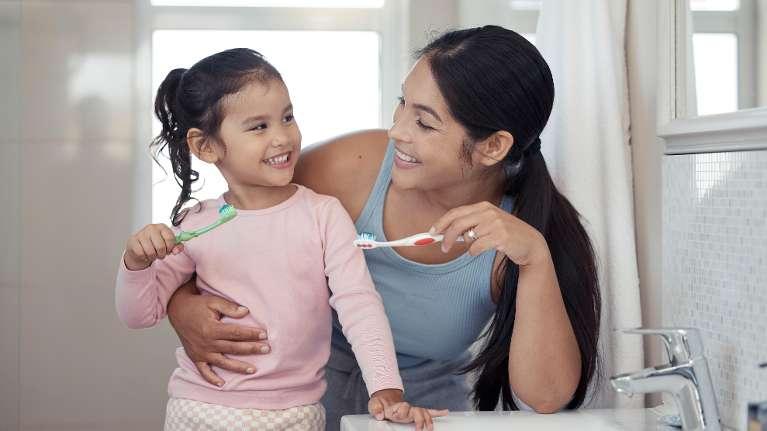 Mother and daughter brushing their teeth