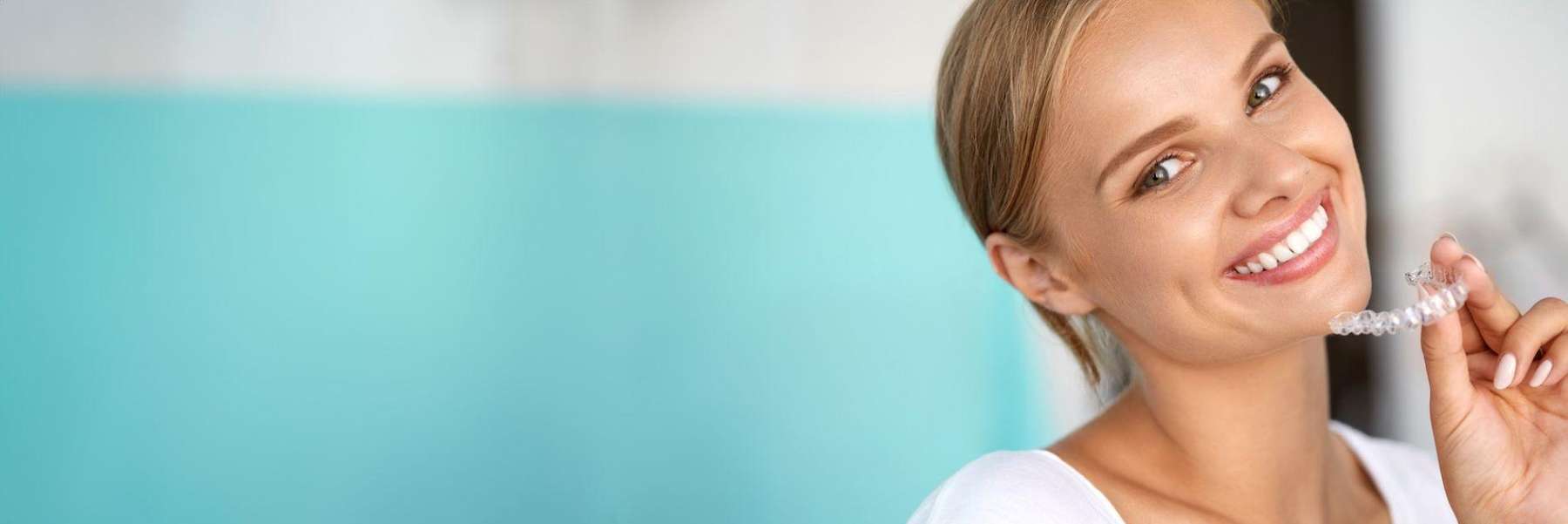A smiling woman holding her Invisalign tray 