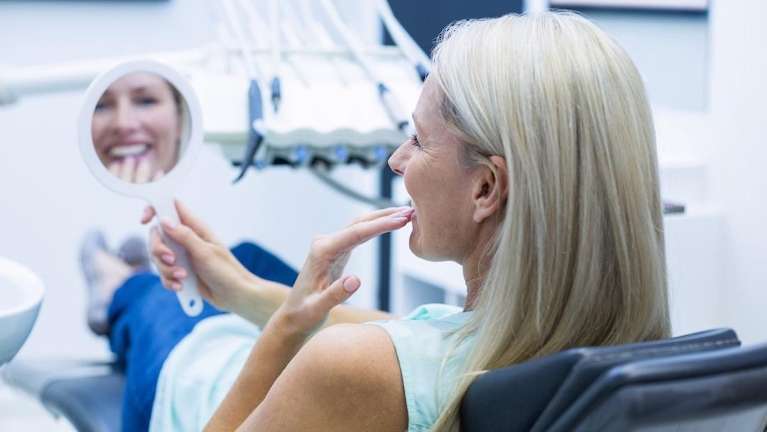 woman smiling in mirror | invisalign clifton hill vic