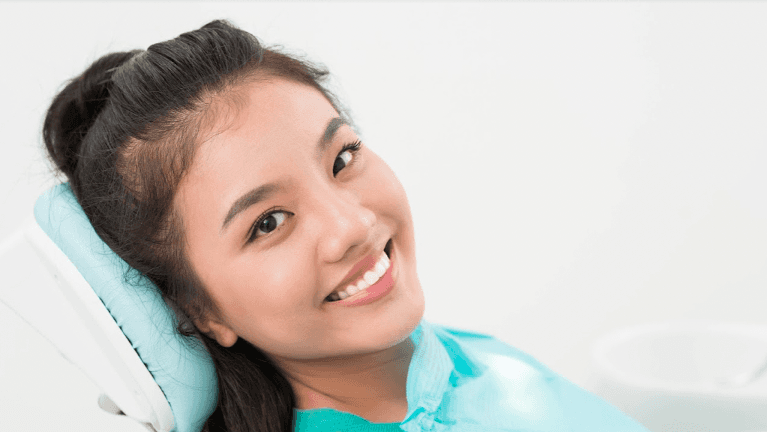 woman laying in dentist chair smiling | bruxism treatment clifton hill vic