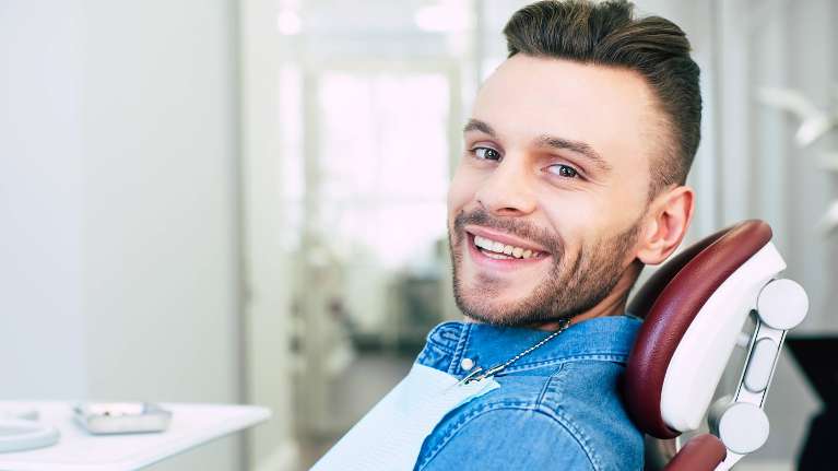 man sitting in dentist exam chair smiling | dental implants clifton hill vic