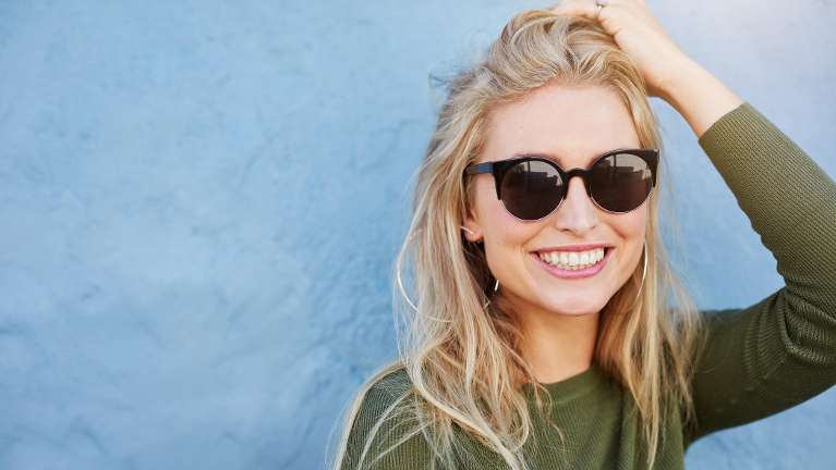 A smiling woman wearing sunglasses
