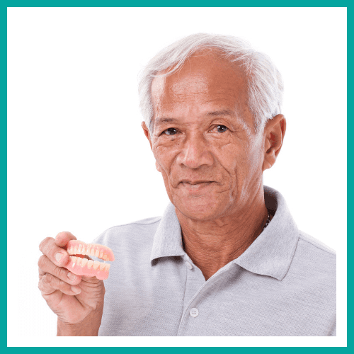 An older man holding his dentures